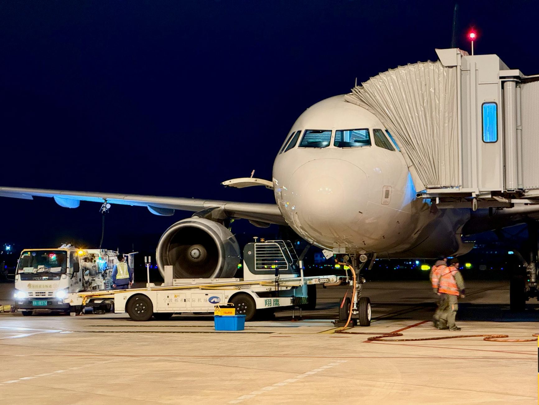 Avión conectado a una manga de embarque de noche, en operaciones de pista
